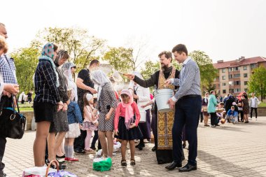 Beryoza, Belarus - 27 Nisan 2019: Rahip, Hristiyan dini geleneklerine göre, inançlıları ve Paskalya pastalarını, yumurta ve mumları kilisenin yakınında kutsal suyla boyadı..