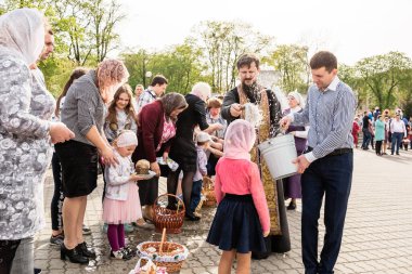 Beryoza, Belarus - 27 Nisan 2019: Rahip, Hristiyan dini geleneklerine göre, inançlıları ve Paskalya pastalarını, yumurta ve mumları kilisenin yakınında kutsal suyla boyadı..