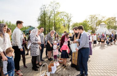Beryoza, Belarus - 27 Nisan 2019: Rahip, Hristiyan dini geleneklerine göre, inançlıları ve Paskalya pastalarını, yumurta ve mumları kilisenin yakınında kutsal suyla boyadı..