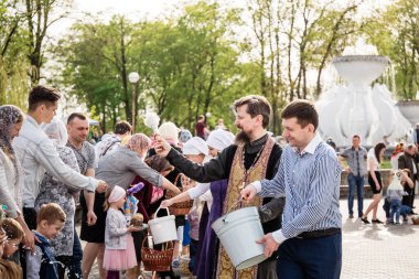Beryoza, Belarus - 27 Nisan 2019: Rahip, Hristiyan dini geleneklerine göre, inançlıları ve Paskalya pastalarını, yumurta ve mumları kilisenin yakınında kutsal suyla boyadı..