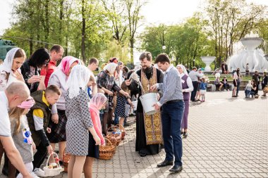 Beryoza, Belarus - 27 Nisan 2019: Rahip, Hristiyan dini geleneklerine göre, inançlıları ve Paskalya pastalarını, yumurta ve mumları kilisenin yakınında kutsal suyla boyadı..