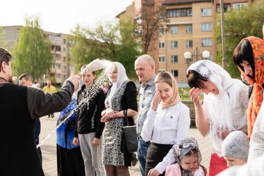 Beryoza, Belarus - 27 Nisan 2019: Rahip, Hristiyan dini geleneklerine göre, inançlıları ve Paskalya pastalarını, yumurta ve mumları kilisenin yakınında kutsal suyla boyadı..
