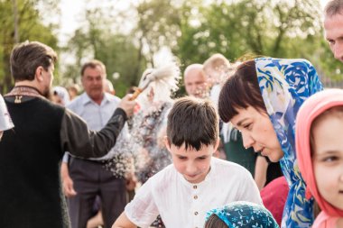 Beryoza, Belarus - 27 Nisan 2019: Rahip, Hristiyan dini geleneklerine göre, inançlıları ve Paskalya pastalarını, yumurta ve mumları kilisenin yakınında kutsal suyla boyadı..