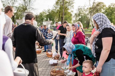 Beryoza, Belarus - 27 Nisan 2019: Rahip, Hristiyan dini geleneklerine göre, inançlıları ve Paskalya pastalarını, yumurta ve mumları kilisenin yakınında kutsal suyla boyadı..