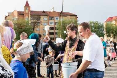 Beryoza, Belarus - 27 Nisan 2019: Rahip, Hristiyan dini geleneklerine göre, inançlıları ve Paskalya pastalarını, yumurta ve mumları kilisenin yakınında kutsal suyla boyadı..
