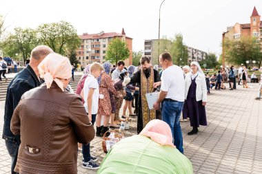 Beryoza, Belarus - 27 Nisan 2019: Rahip, Hristiyan dini geleneklerine göre, inançlıları ve Paskalya pastalarını, yumurta ve mumları kilisenin yakınında kutsal suyla boyadı..