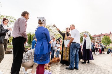 Beryoza, Belarus - 27 Nisan 2019: Rahip, Hristiyan dini geleneklerine göre, inançlıları ve Paskalya pastalarını, yumurta ve mumları kilisenin yakınında kutsal suyla boyadı..