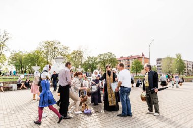 Beryoza, Belarus - 27 Nisan 2019: Rahip, Hristiyan dini geleneklerine göre, inançlıları ve Paskalya pastalarını, yumurta ve mumları kilisenin yakınında kutsal suyla boyadı..
