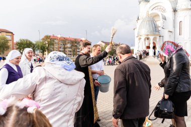 Beryoza, Belarus - 27 Nisan 2019: Rahip, Hristiyan dini geleneklerine göre, inançlıları ve Paskalya pastalarını, yumurta ve mumları kilisenin yakınında kutsal suyla boyadı..