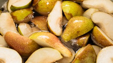 Bir çeyrekte dilimlenmiş tatlı armutlar turtaya ya da reçel şeklinde konserveye hazırlanmak için şekerle pişirilir. Kendi meyve suyunu yakın plan dilimler..