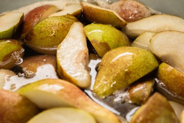 Bir çeyrekte dilimlenmiş tatlı armutlar turtaya ya da reçel şeklinde konserveye hazırlanmak için şekerle pişirilir. Kendi meyve suyunu yakın plan dilimler..