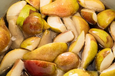 Bir çeyrekte dilimlenmiş tatlı armutlar turtaya ya da reçel şeklinde konserveye hazırlanmak için şekerle pişirilir. Kendi meyve suyunu yakın plan dilimler..