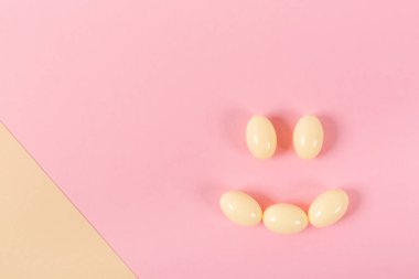 Gülümseme şeklinde pembe bir arka planda hapların ve kapsüllerin bileşimi. Mutlu duygular. Psikolojik yardım. İyi günler..