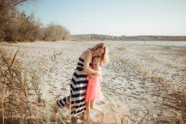 Güneşli bir gün, anne ve kızı sarılıp sohbet ediyorlar. Yaz tatili ya da hafta sonu sahilde tatil. Çocukla yalnız bir annenin iletişim psikolojisi. Yakın plan..