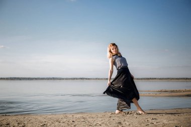 Genç bir kadın gölde dans ediyor, gülüyor ve gülümsüyor, harika bir ruh hali ve sportif bir vücudu var. Özgürlük ve bağımsızlık hissi. Kendine zaman ayır. Doğa ve hareket duygusal çöküntünün bir aracı olarak. Yan görünüm.