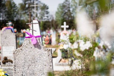 Üzerinde bir mezar taşı ve haç olan merhumun mezarı. Ölülerin Bahar Günü anısına. Akrabalarımızın, dostlarımızın, akrabalarımızın ve atalarımızın ruhları için dua ediyoruz. Önde çiçek açan bir kiraz dalı var..