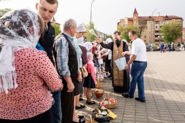 Beryoza, Belarus - 27 Nisan 2019: Rahip, Hristiyan dini geleneklerine göre, inançlıları ve Paskalya pastalarını, yumurta ve mumları kilisenin yakınında kutsal suyla boyadı..