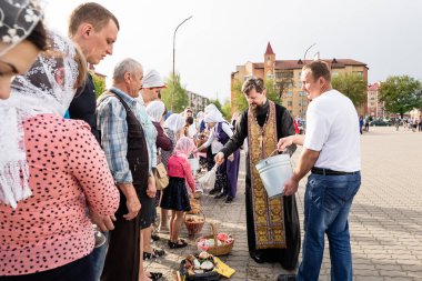 Beryoza, Belarus - 27 Nisan 2019: Rahip, Hristiyan dini geleneklerine göre, inançlıları ve Paskalya pastalarını, yumurta ve mumları kilisenin yakınında kutsal suyla boyadı..