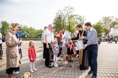 Beryoza, Belarus - 27 Nisan 2019: Rahip, Hristiyan dini geleneklerine göre, inançlıları ve Paskalya pastalarını, yumurta ve mumları kilisenin yakınında kutsal suyla boyadı..