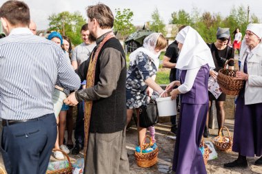Beryoza, Belarus - 27 Nisan 2019: Rahip, Hristiyan dini geleneklerine göre, inançlıları ve Paskalya pastalarını, yumurta ve mumları kilisenin yakınında kutsal suyla boyadı..