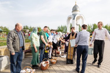 Beryoza, Belarus - 27 Nisan 2019: Rahip, Hristiyan dini geleneklerine göre, inançlıları ve Paskalya pastalarını, yumurta ve mumları kilisenin yakınında kutsal suyla boyadı..