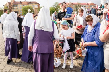 Beryoza, Belarus - 27 Nisan 2019: Rahip, Hristiyan dini geleneklerine göre, inançlıları ve Paskalya pastalarını, yumurta ve mumları kilisenin yakınında kutsal suyla boyadı..