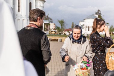 Beryoza, Belarus - 27 Nisan 2019: Rahip, Hristiyan dini geleneklerine göre, inançlıları ve Paskalya pastalarını, yumurta ve mumları kilisenin yakınında kutsal suyla boyadı..