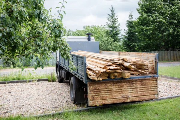 A planed board lies on board the truck. Building materials were brought to the construction site. Chopped wood for interior use. Cargo transportation of oversized items.