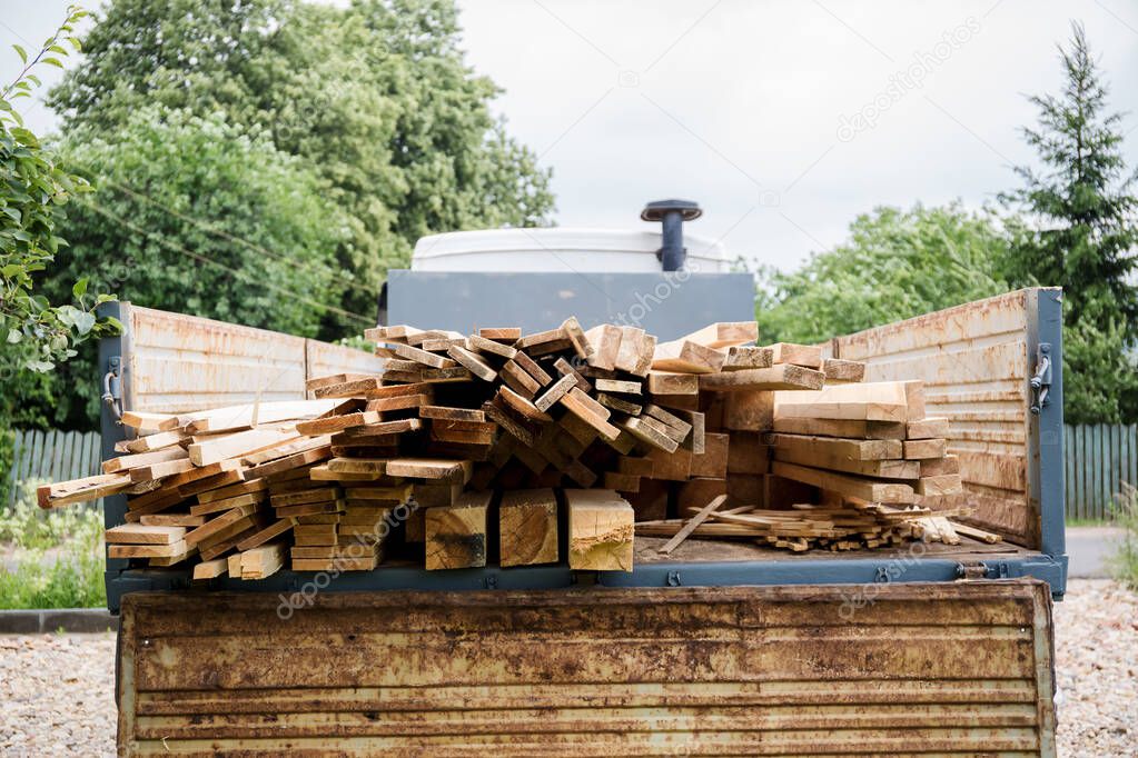 A planed board lies on board the truck. Building materials were brought to the construction site. Chopped wood for interior use. Cargo transportation of oversized items.