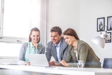 Mutlu genç iş adamları masa ofis dizüstü bilgisayar kullanarak