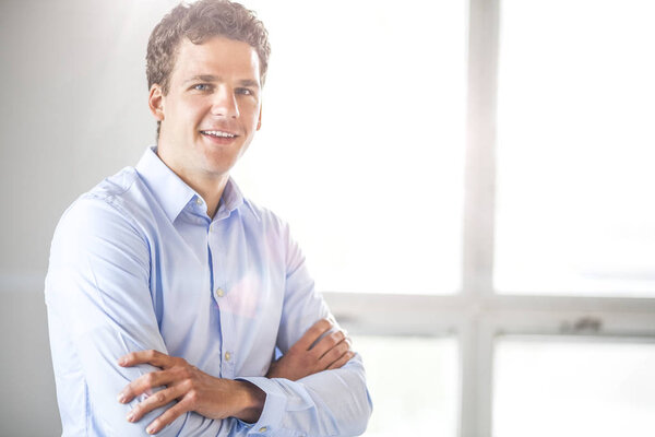 Portrait of businessman standing arms crossed in office