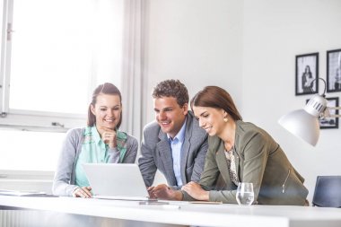 Mutlu genç iş adamları masa ofis dizüstü bilgisayar kullanarak