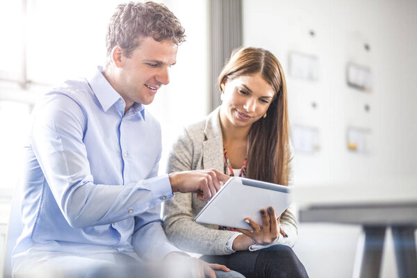 Young businessman with female colleague using digital tablet at office