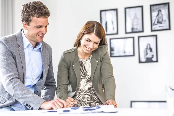 Young business people discussing over brochure at desk in office