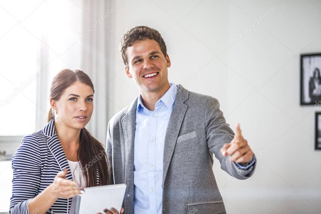 Happy young businessman showing something to female colleague in office