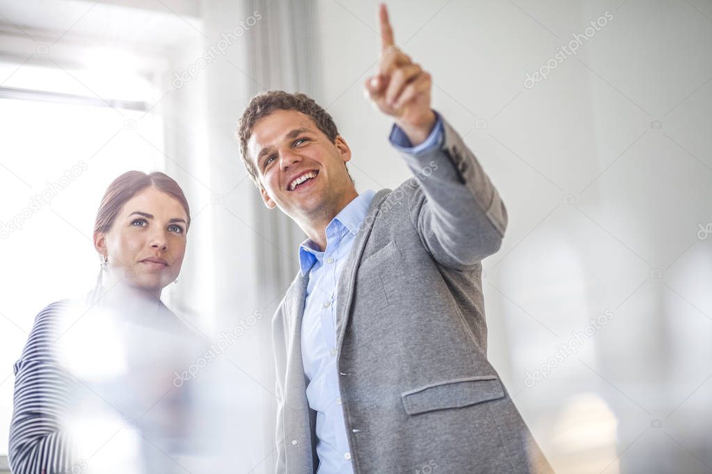 Happy young businessman showing something to female colleague in office