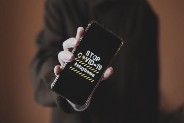 Eldivenli akıllı telefonun yakın planında koronavirüs görüntüsü var. COVID-19 'un Görüntü. 