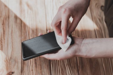 COVID-19 Coronavirus salgınını önleme amaçlı temizlik için cep telefonu ekranını ıslak mendillerle dezenfekte etmek.