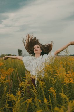 Doğa arka planında klasik elbiseli bir kızın portresi. Güneşli bir yaz gününde tarlada uzun saçlı bir kız. Eski moda elbise..