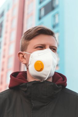 Virüs salgınının karantinası sırasında ıssız bir sokakta koruyucu maske takmış bir adamın portresi. Virüs salgınının karantinası sırasındaki bir insanın kıyafeti..
