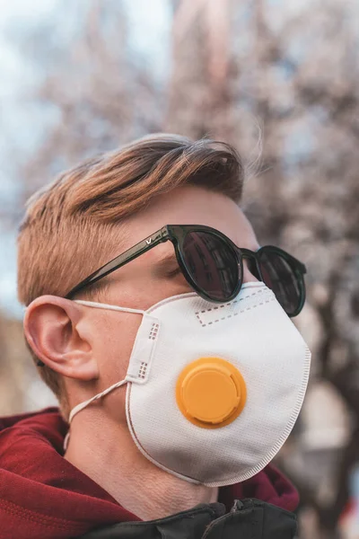 Portrait of a man in a protective mask respirator on a deserted street during quarantine of a virus epidemic. Outfit of a person during quarantine of a virus epidemic.