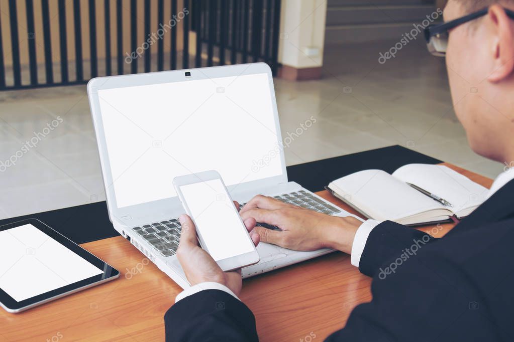 Businessman working on laptop and smart phone.