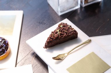 Çikolatalı pasta ve mermer tabakta yabanmersinli turta ve bir restoranda altın kaşık..