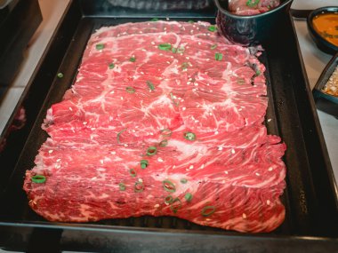 Restorandaki Japon masasında siyah seramik tabakta panzu soslu wagyu eti dilimleri..