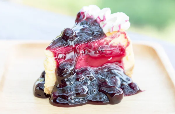 レストランで木のテーブルの上に木製のプレート上のクリームとブルーベリーチーズケーキ — ストック写真