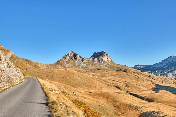 Rotsachtige bergen bedekt met herfstweide tegen de blauwe lucht — Stockfoto