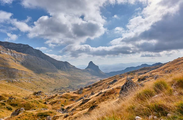 Rotsachtige bergen bedekt met herfstweide tegen de achtergrond van een stormachtige hemel — Stockfoto