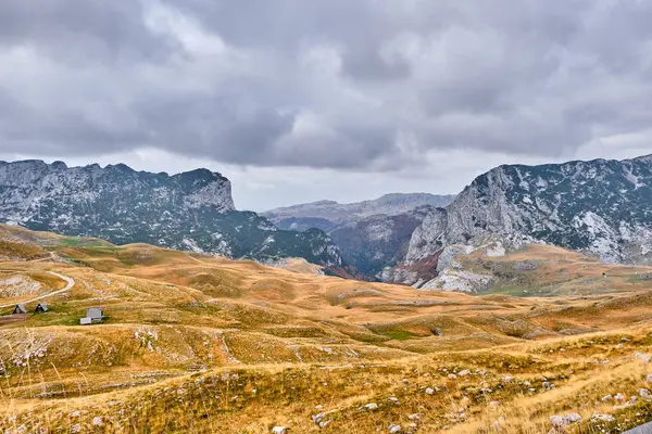 Rotsachtige bergen bedekt met herfstweide tegen de achtergrond van een stormachtige hemel — Stockfoto