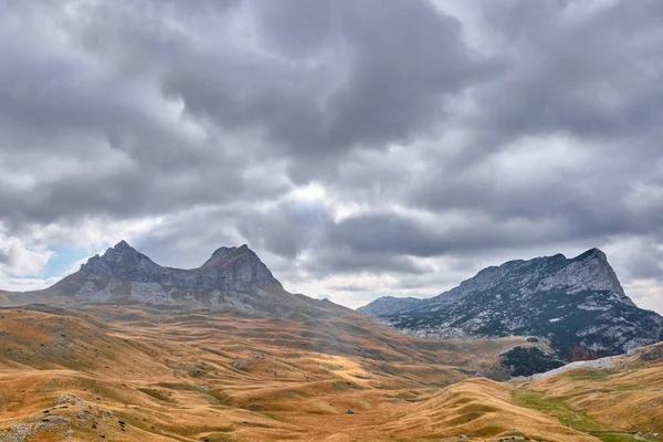 Rotsachtige bergen bedekt met herfstweide tegen de achtergrond van een stormachtige hemel — Stockfoto