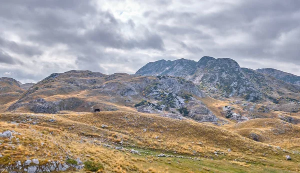 Rotsachtige bergen bedekt met herfstweide tegen de achtergrond van een stormachtige hemel — Stockfoto